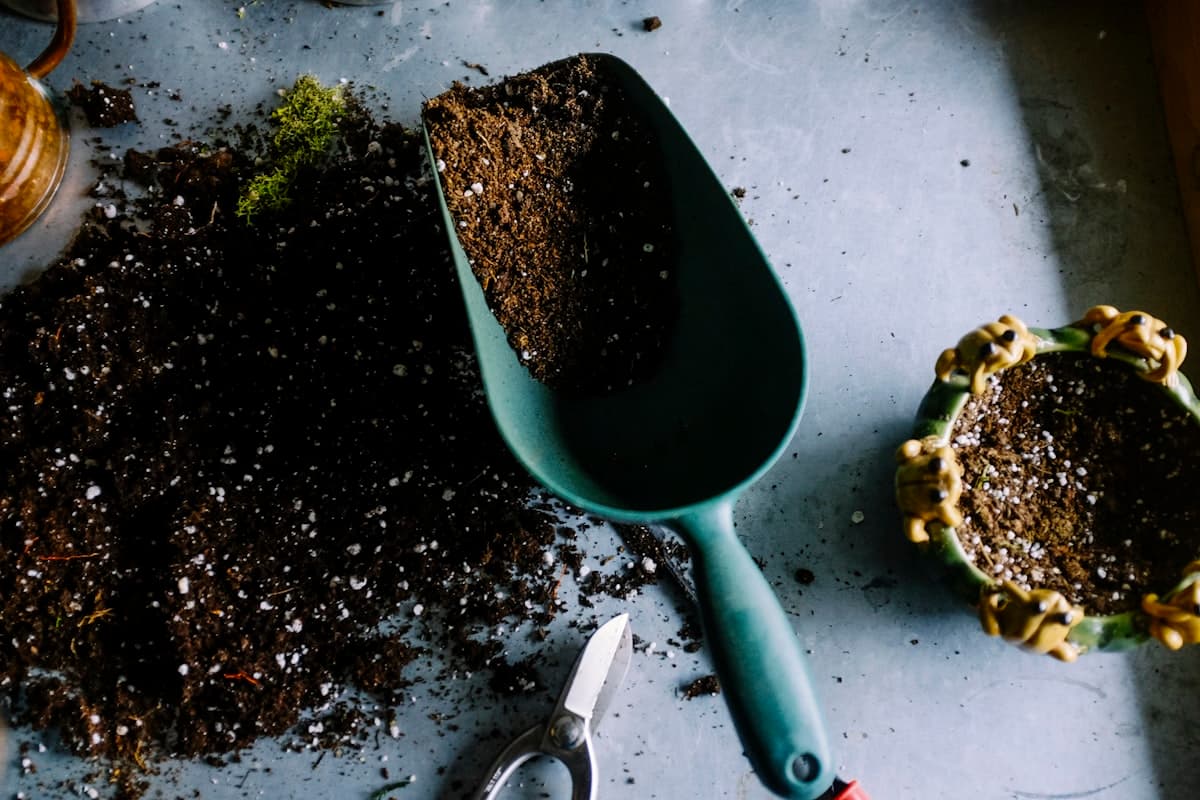 A trowel, soil, and planting pots on a working garden table
